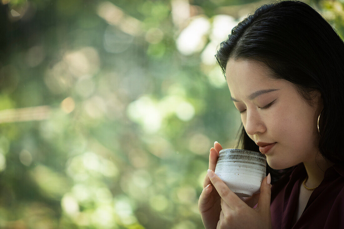 Young woman drinking tea at window