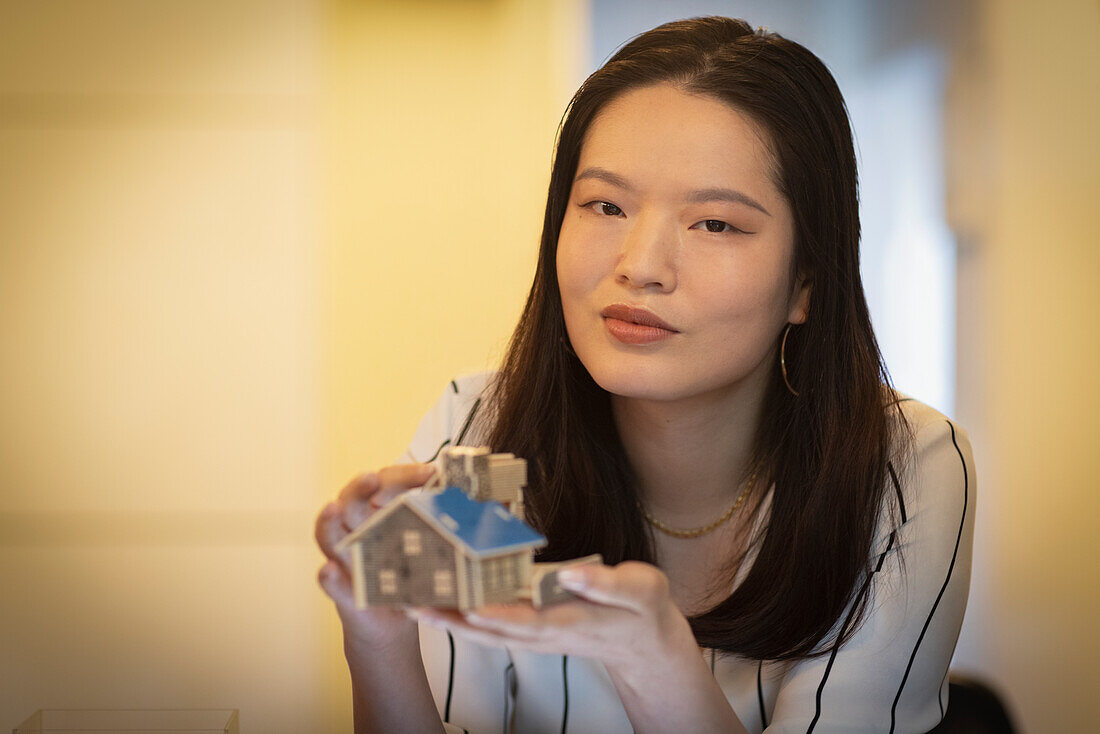 Female architect holding tiny house model