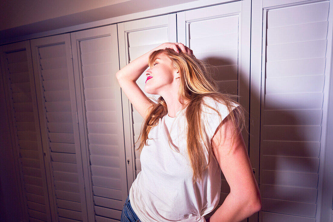 Carefree young woman standing at shuttered windows