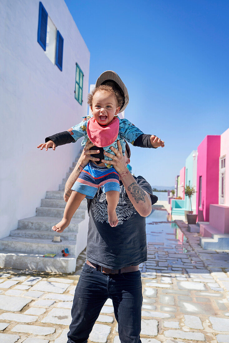Father holding toddler boy on sunny street
