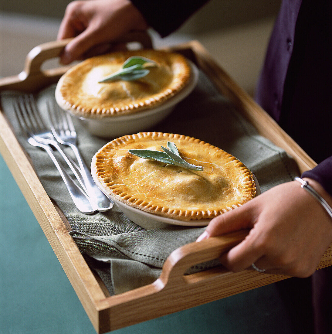 Person serving beef pot pie on wooden tray