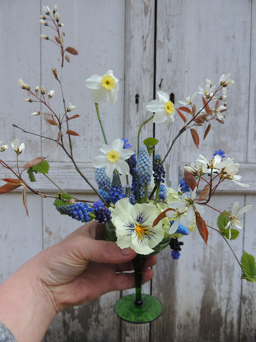 Gesteck aus Frühlingsblumen im grünen Glas