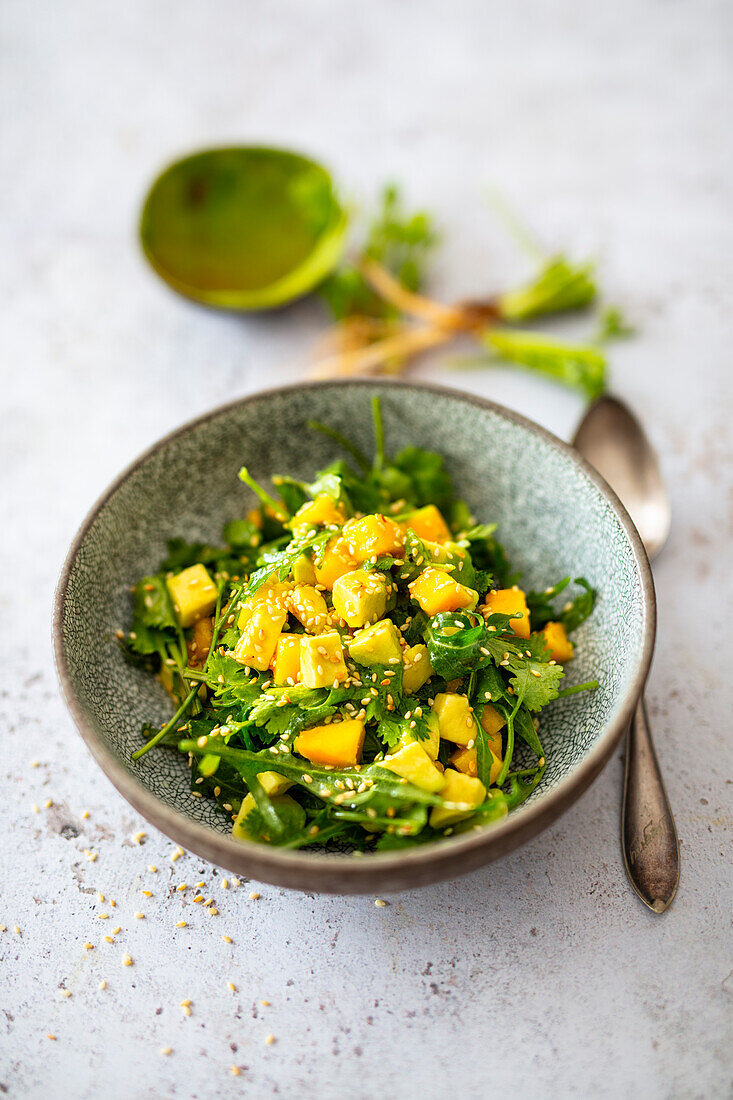 Salad with mango, avocado, coriander greens, rocket and sesame seeds