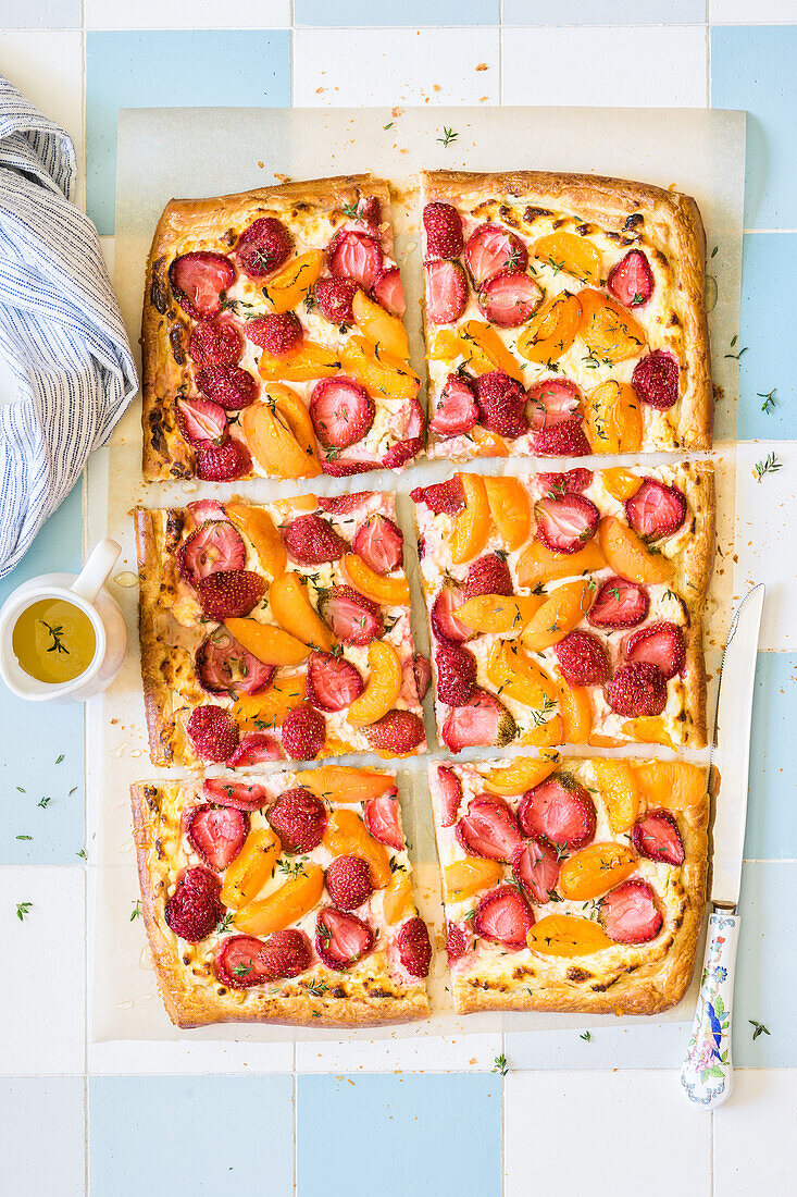 Sliced puff pastry tart with cottage cheese, strawberries, apricots, thyme and honey