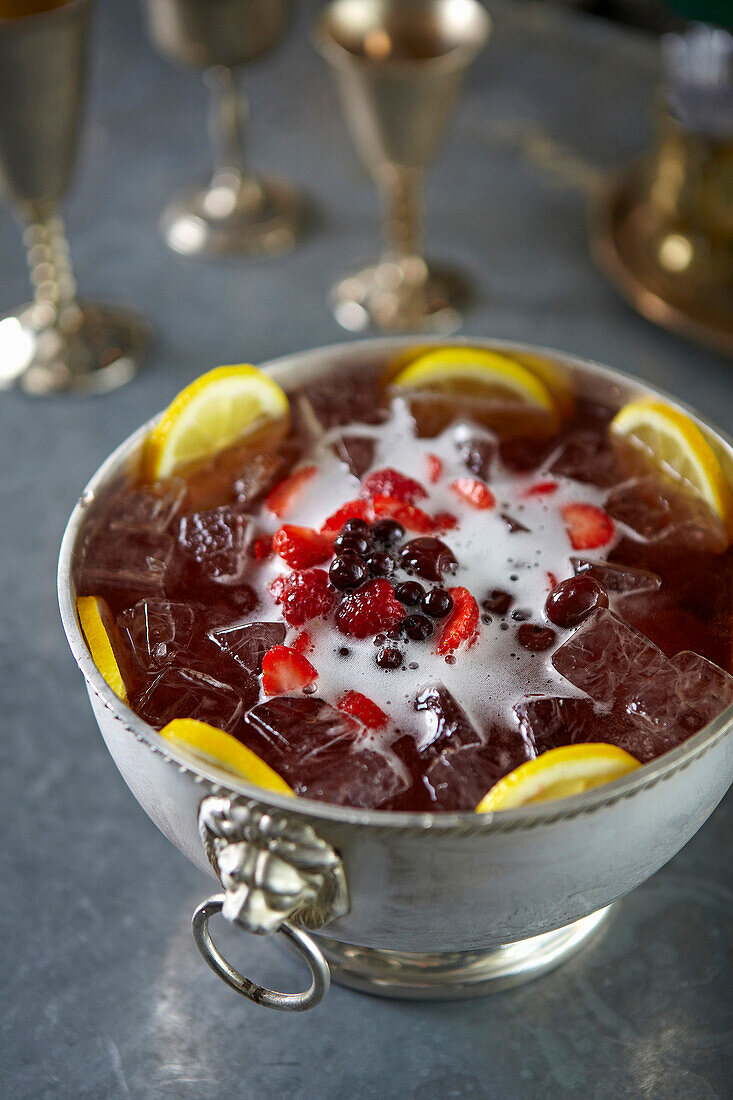 Iced tea with berries, lemon slices and ice cubes