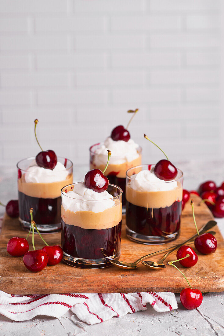 Layered dessert with fruit jelly peanut butter cream and cherries in a glass