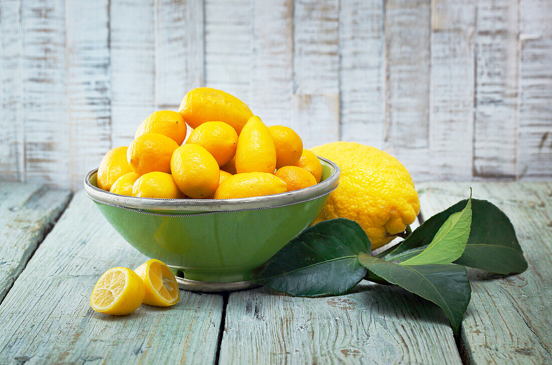 Snack-Zitronen in einer Schale, daneben Zitrone mit Blättern