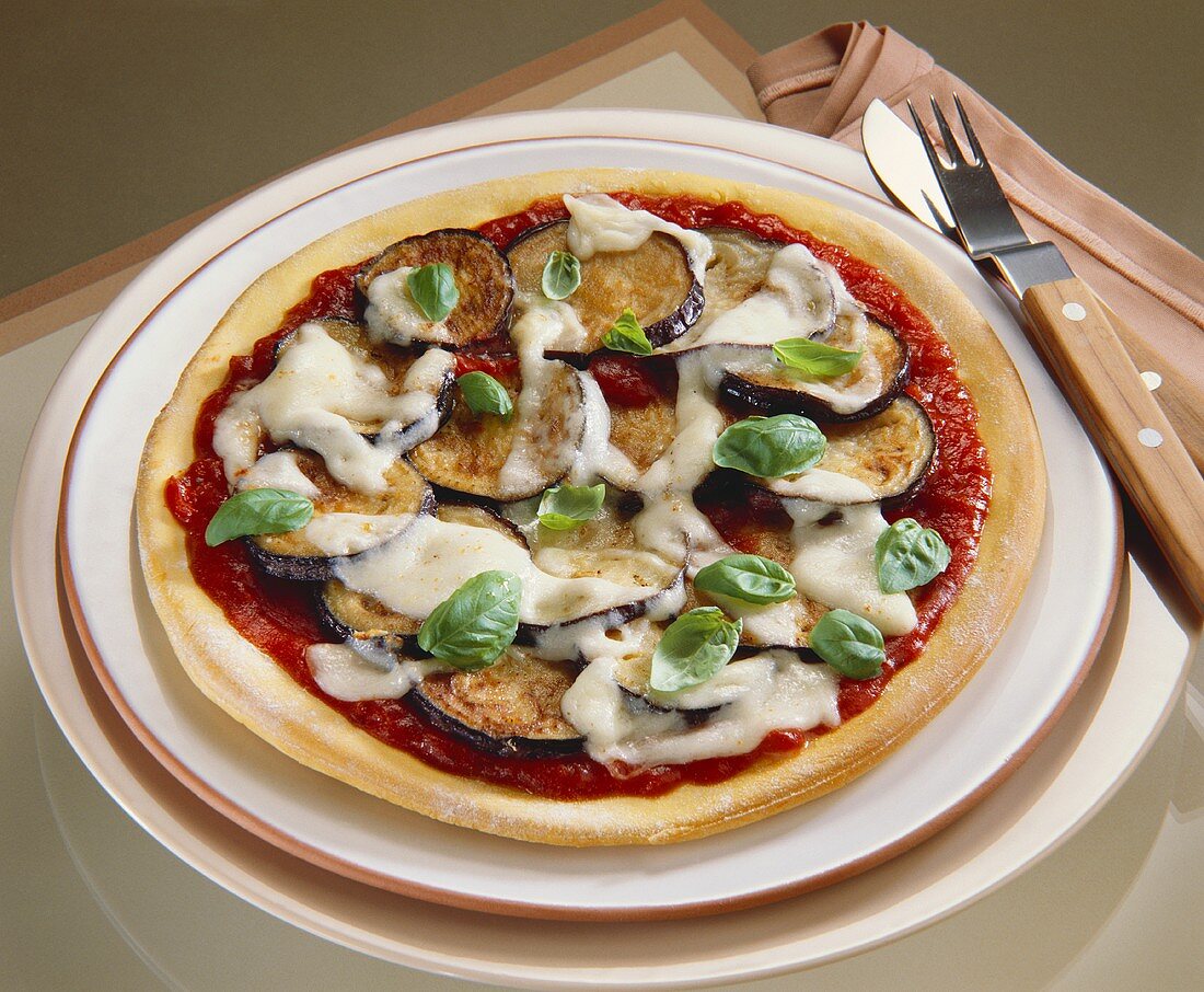 Pizza with tomato and aubergine topping, mozzarella and basil