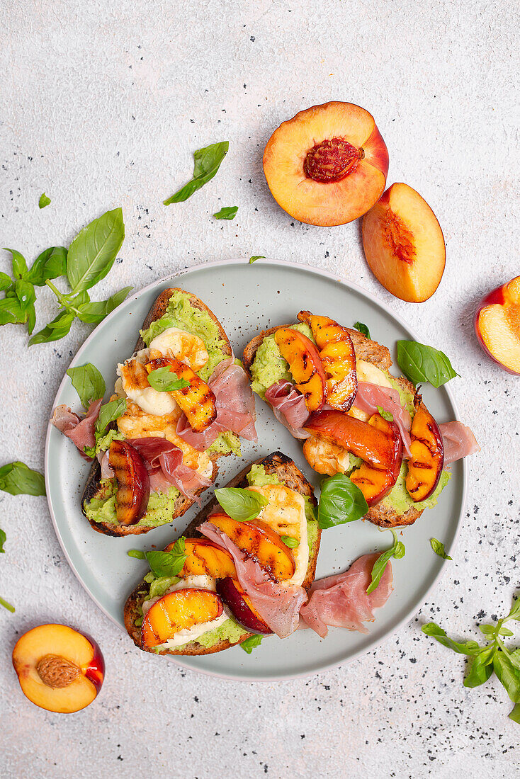 Toasted bread with bean and pea paste, halloumi, grilled peach, ham, and basil