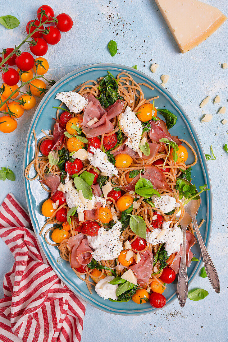 Wholewheat spaghetti with roasted cherry tomatoes, burrata, spinach, and Parma ham