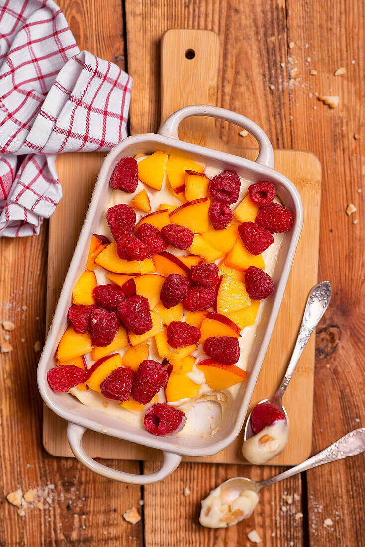 Summer tiramisu with vanilla cream, peaches, and raspberries