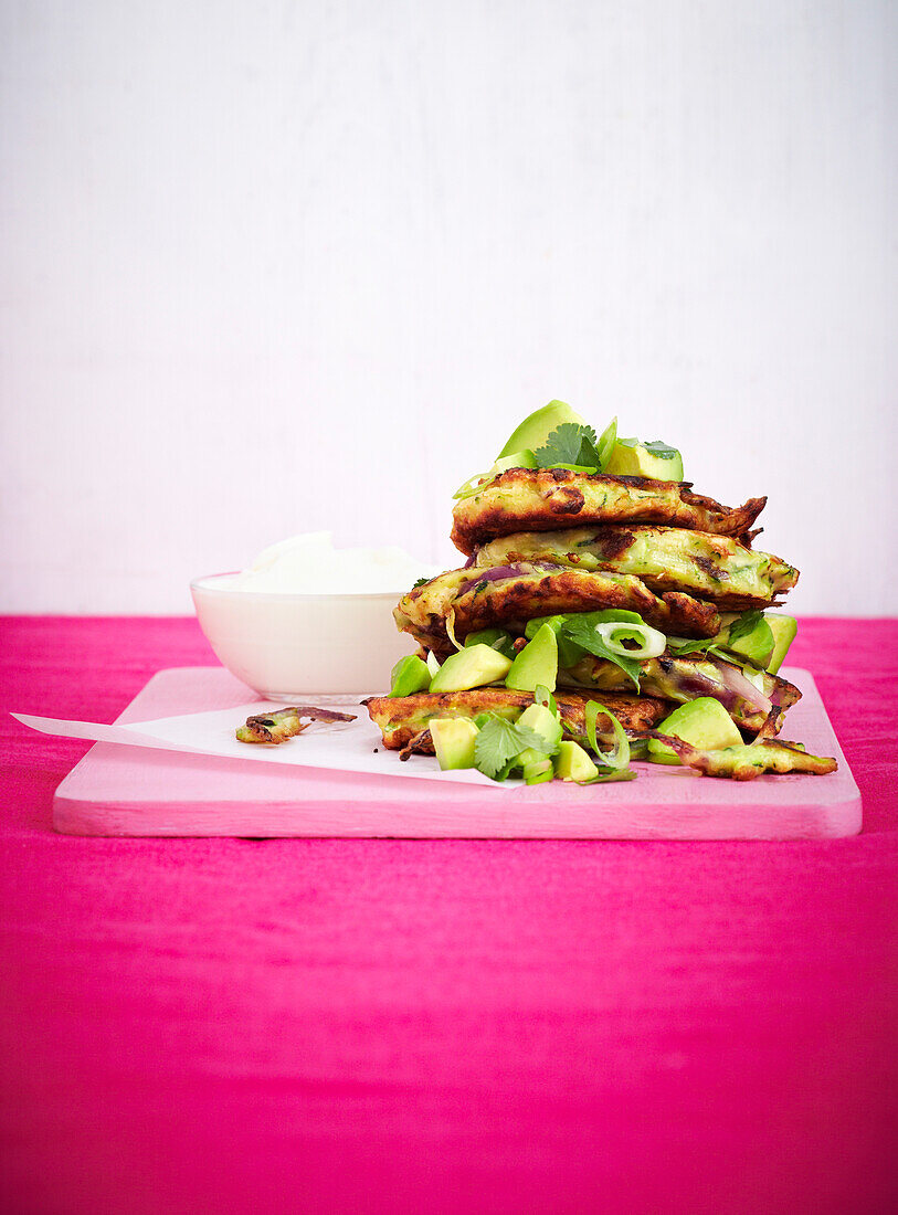 Zucchini-Pancakes mit roten Zwiebeln serviert mit Avocado-Salsa