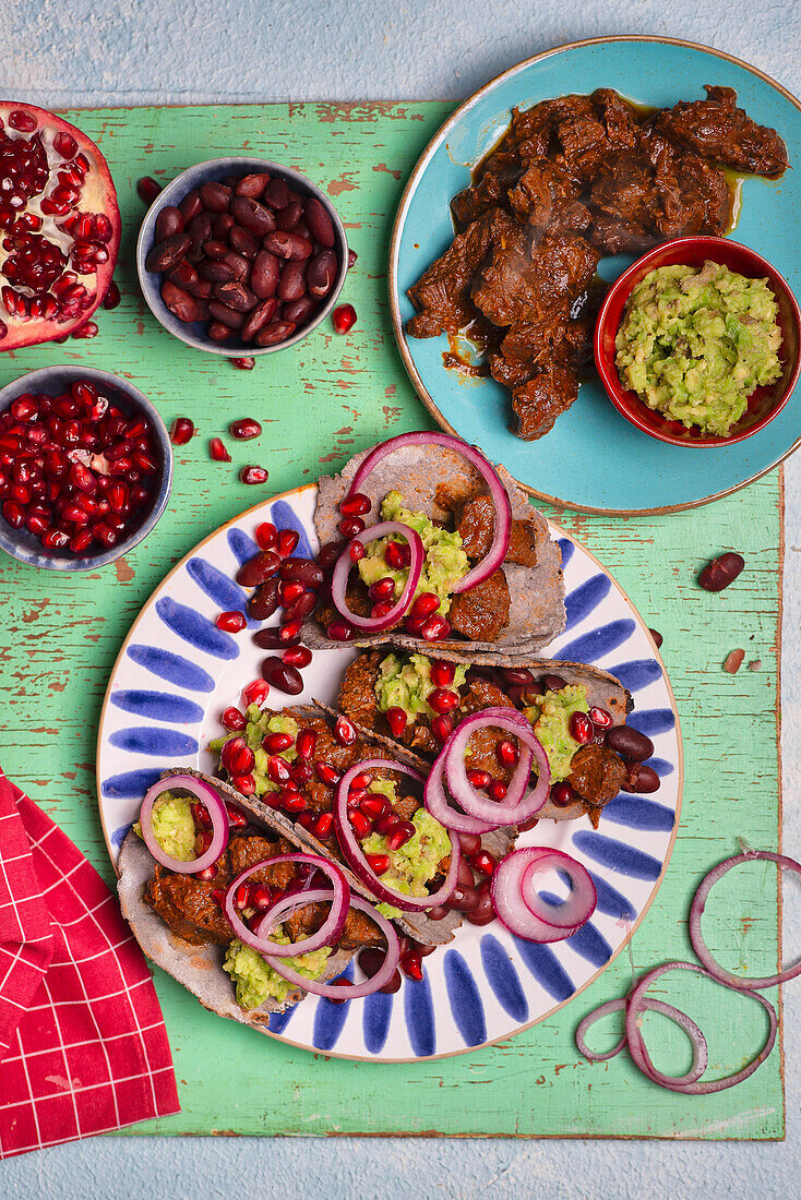 Blue corn flour tacos beef red beans avocado paste pomegranate seeds red onion