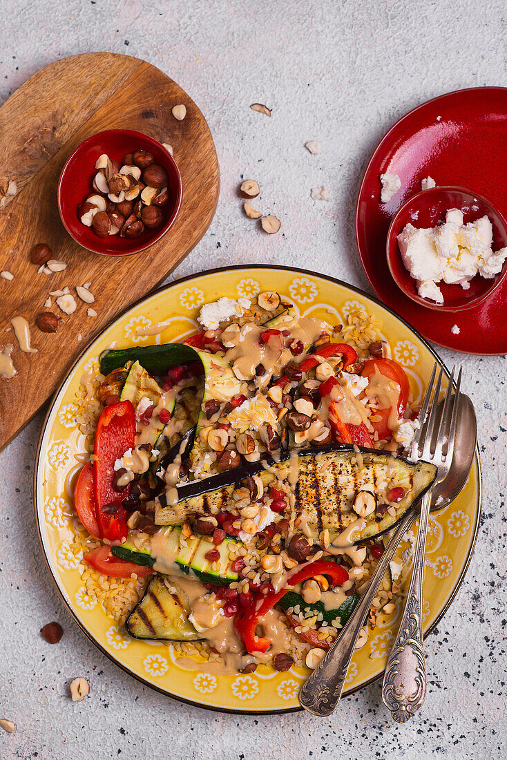 Bulgur mit gegrillten Auberginen, Feta-Käse, Paprika, Haselnüssen, Granatapfelkernen und Tahin-Dressing