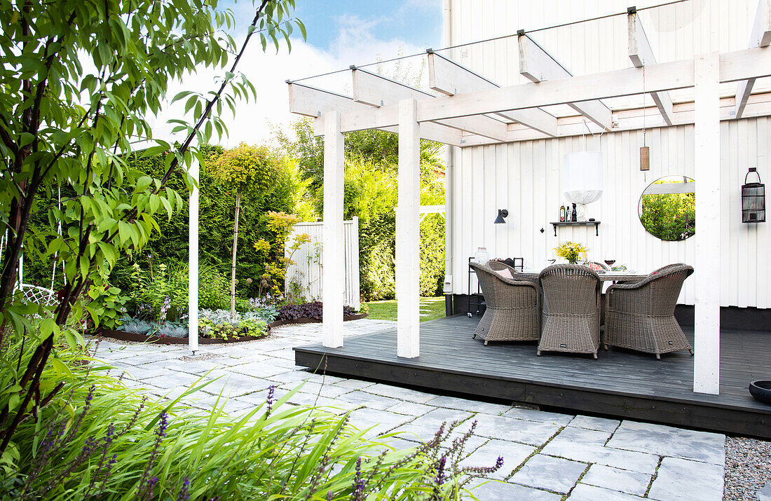 Pergola with glass roof with rattan chairs and table on wooden patio