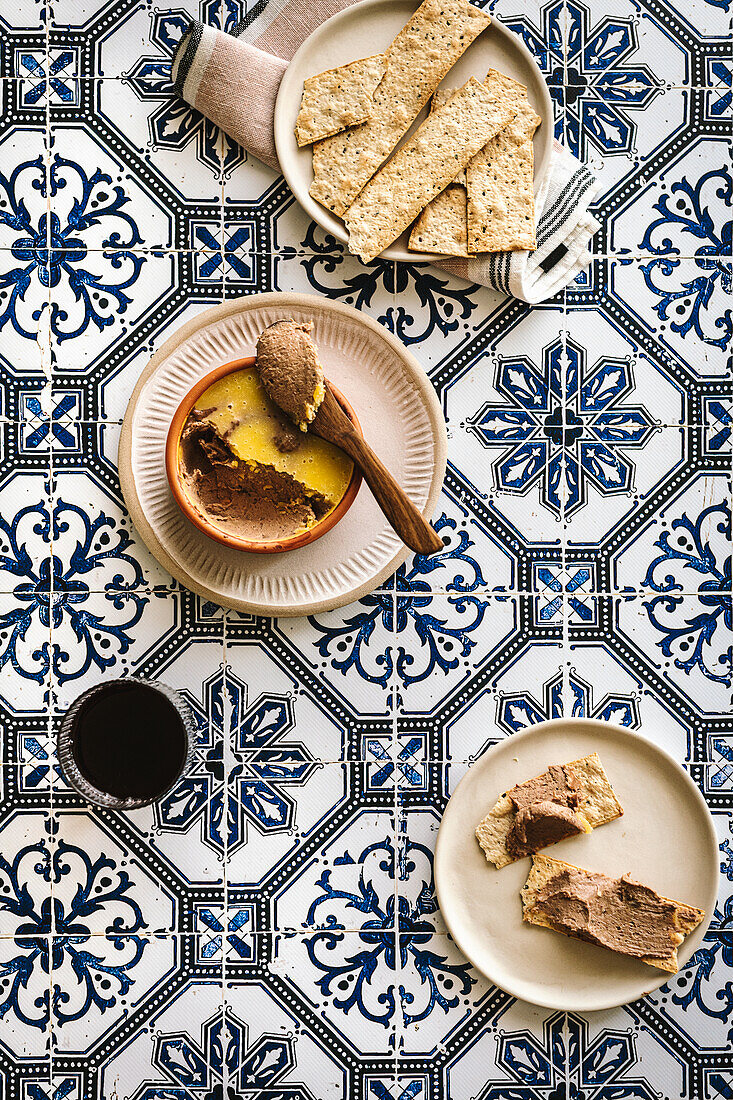 Chicken liver pate with crackers on a tile background