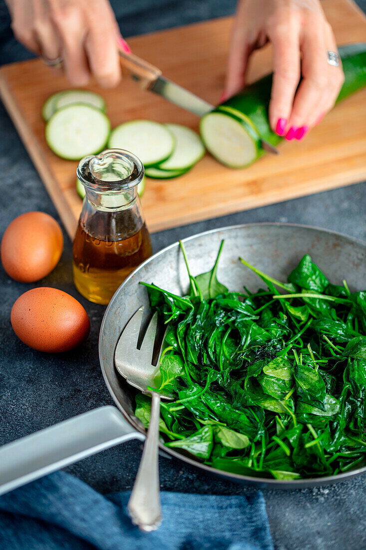 Prepping an egg dish with spinach and zucchini