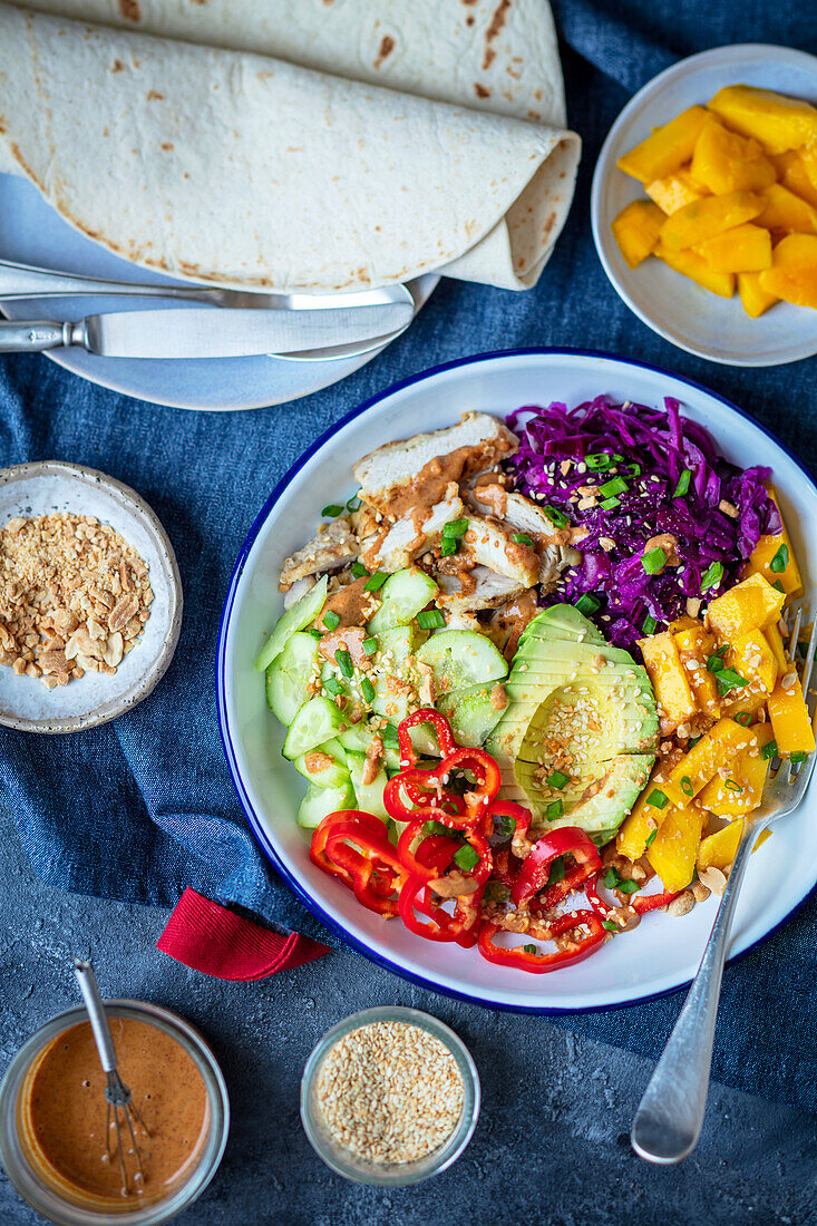 Bowl with chicken, avocado, red cabbage, and mango