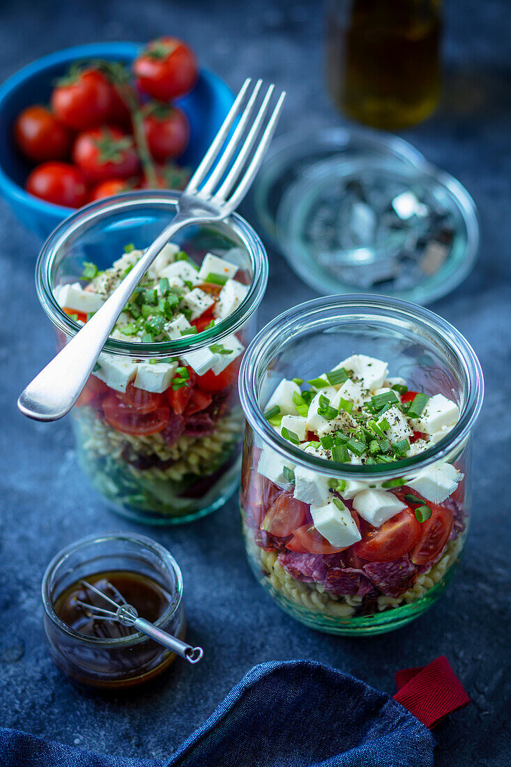 Layered salad in a glass with noodles, vegetables, and mozzarella cheese