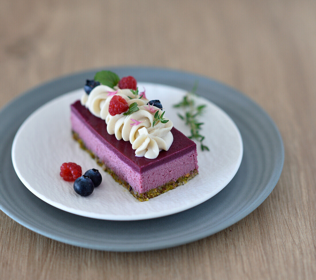 Vegan raspberry mousse tart with a pistachio base and blueberry glaze