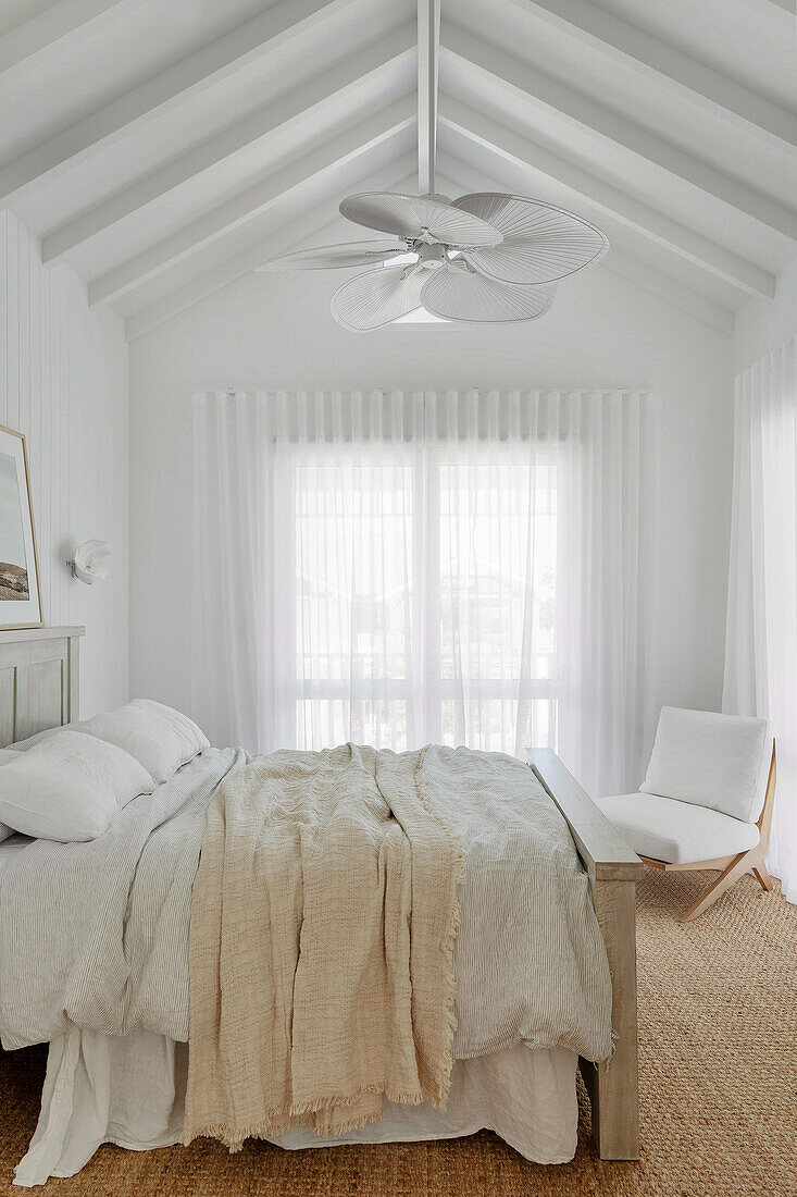 Doppelbett aus Mangoholz und Sessel in weißem Schlafzimmer