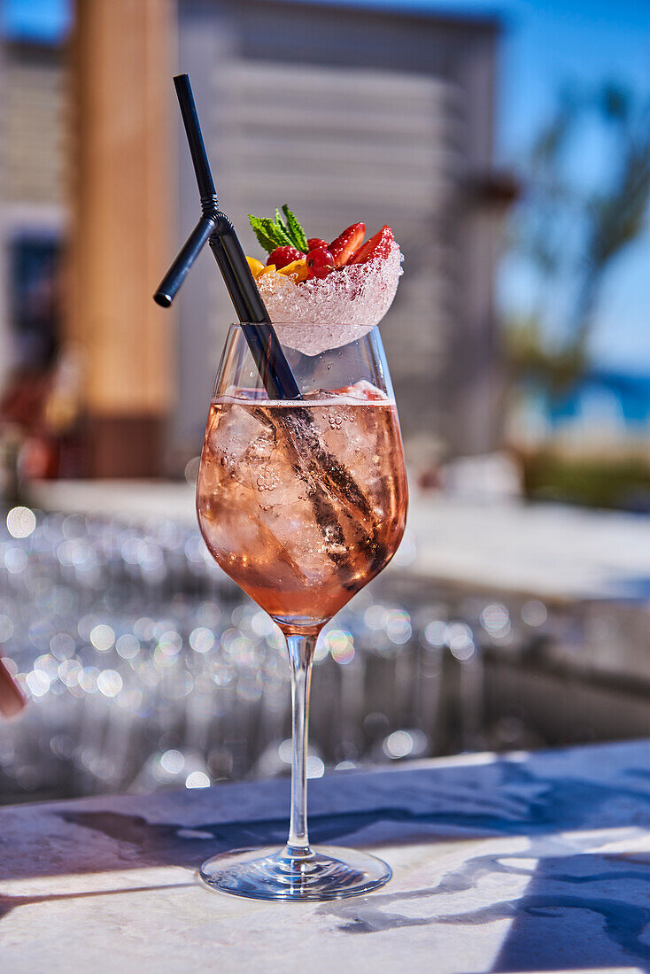 A glass of rosé wine garnished with strawberries