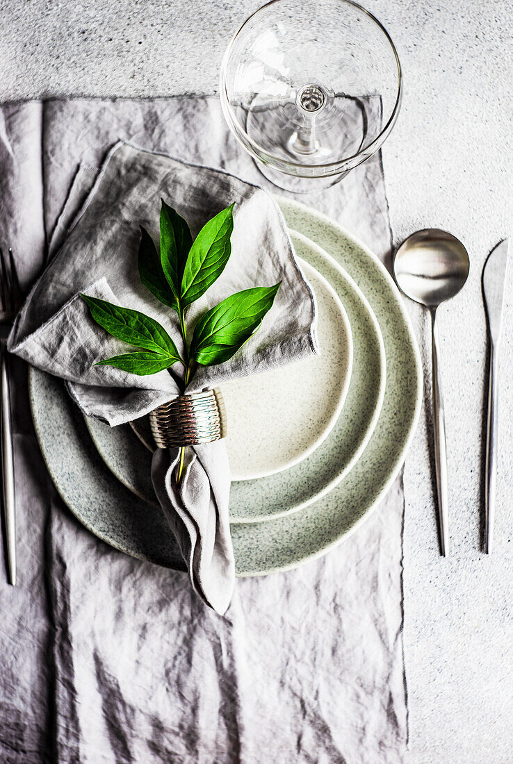 A place setting with a fabric napkin and peony leaves