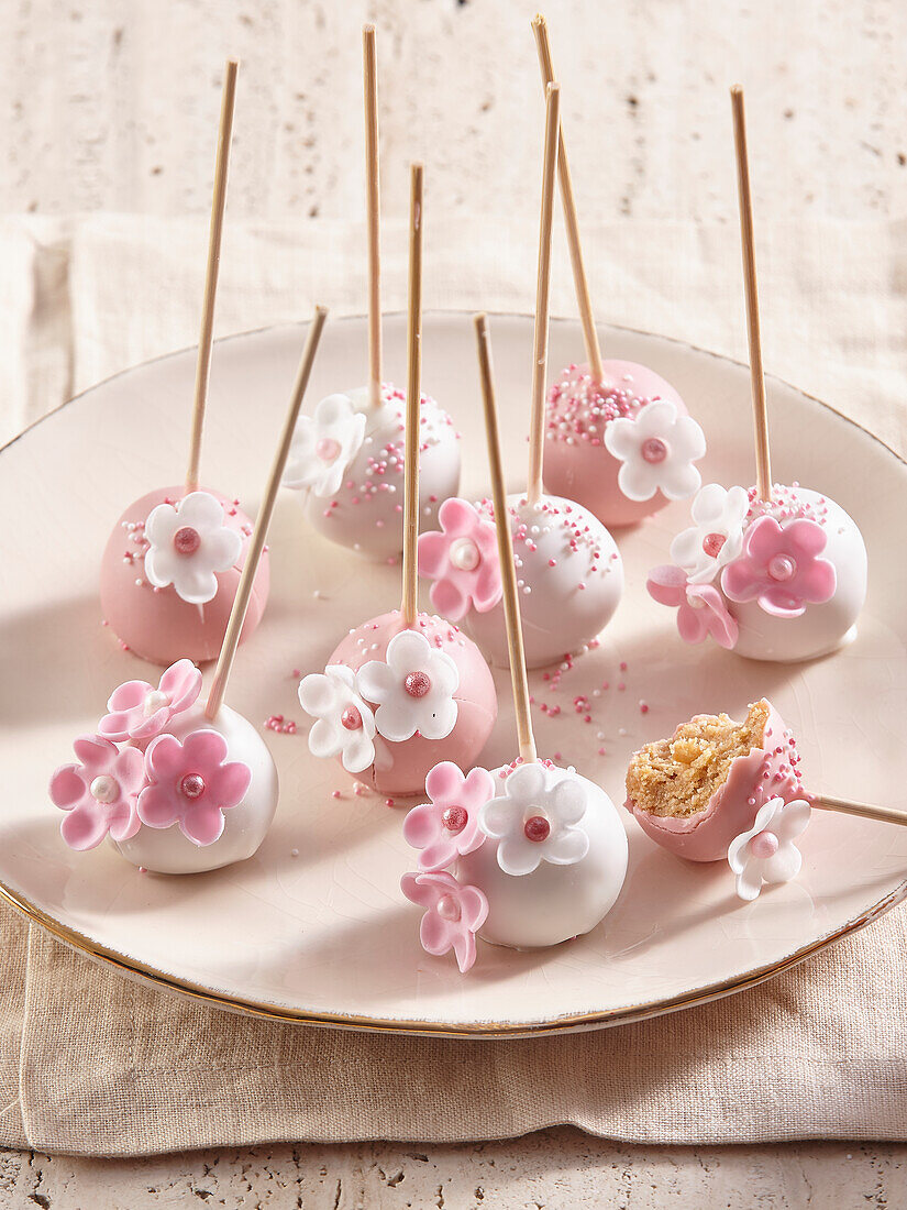Süße rosa-weiße Cake Pops mit Zuckerblüten dekoriert