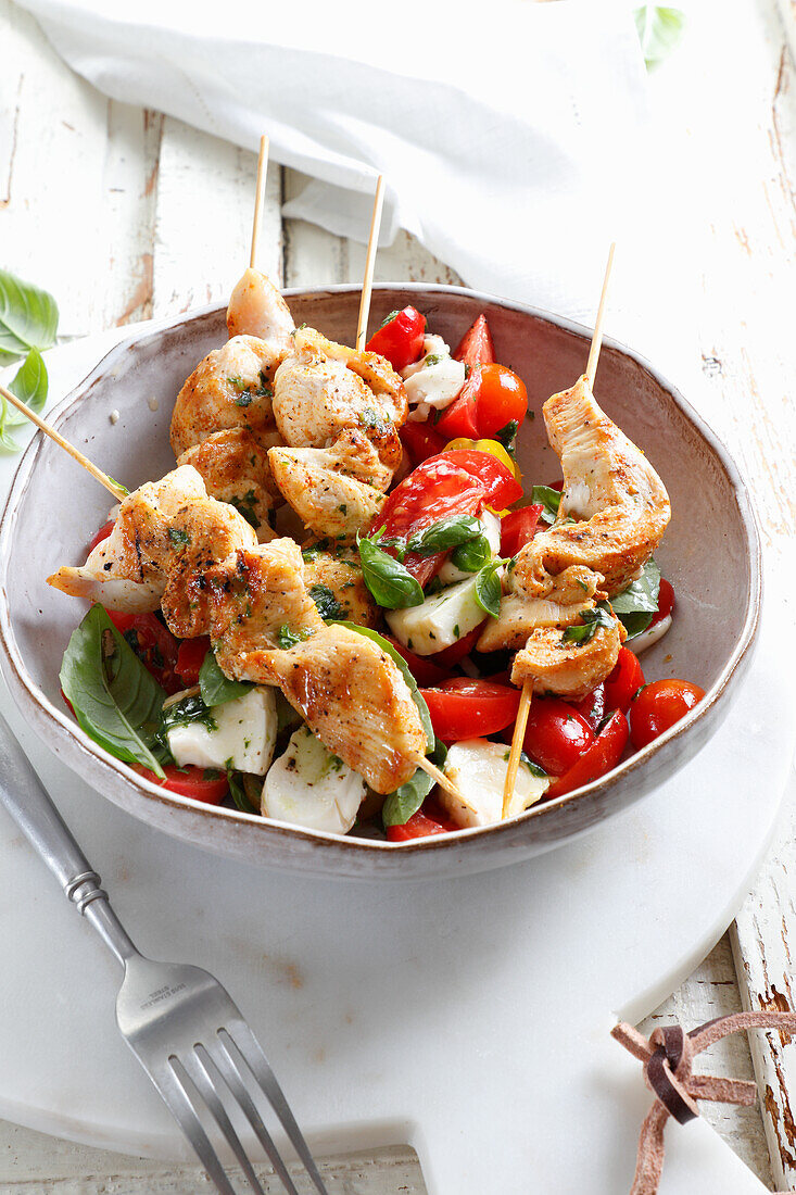 Grilled chicken on a skewer, served with caprese salad