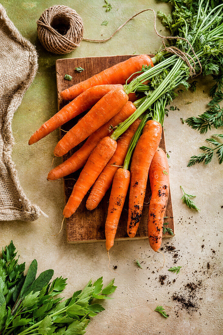 A bunch of carrots with a cut on an old board