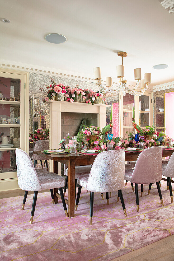 Esszimmer mit üppiger Blumendekoration, gedecktem Tisch und Samtstühlen