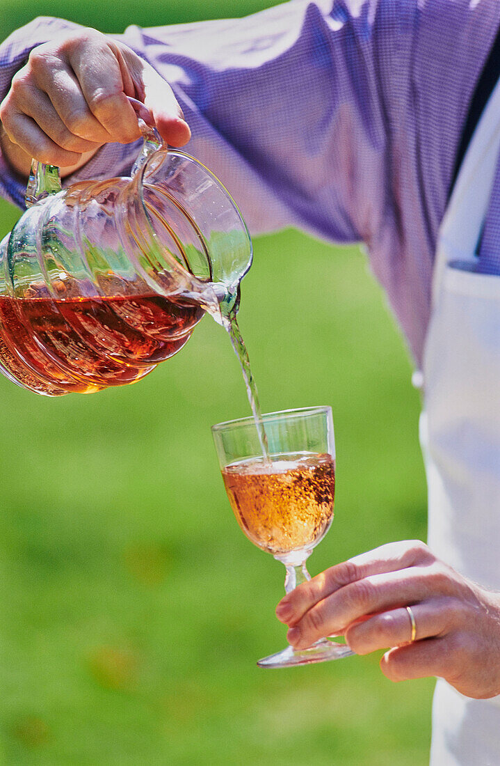 Ein Glas Roséwein einschenken