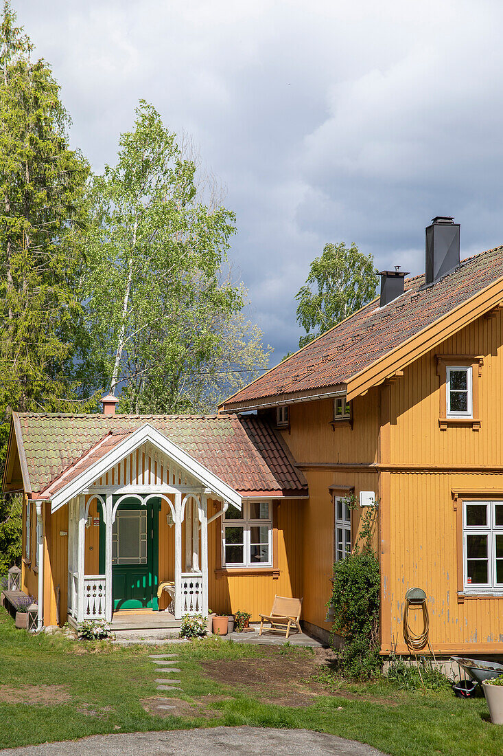 Gelb gestrichenes Holzhaus in ländlicher Umgebung