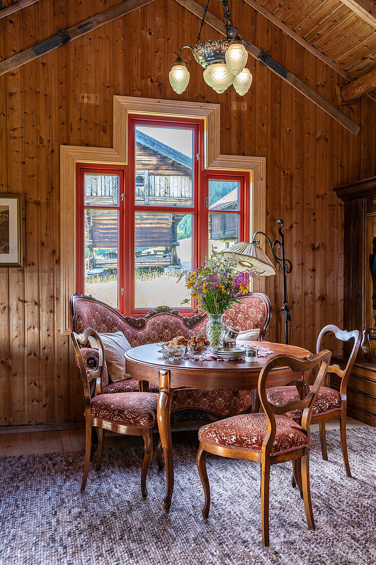 Salon mit antikem Tisch und gepolsterten Sitzmöbeln in einem Chalet