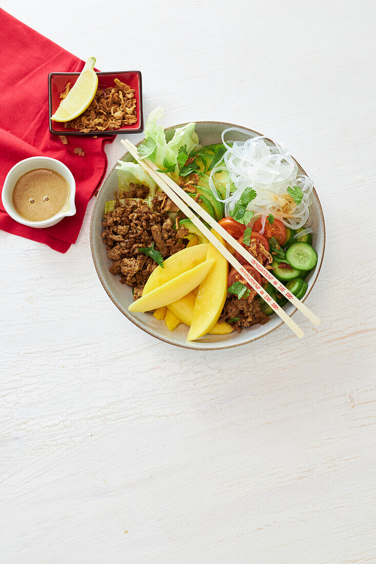 Ground beef noodle bowl with mango, fried onions, and sesame dressing