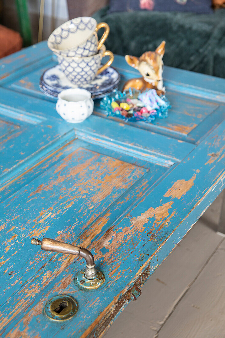 Kaffeetassen und Rehfigur auf blau gestrichener Tür als Tisch
