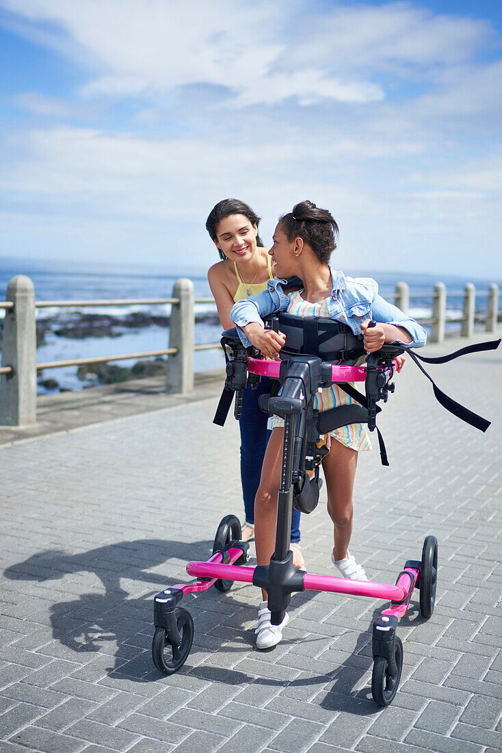 Mother and daughter with rollator walking on boardwalk