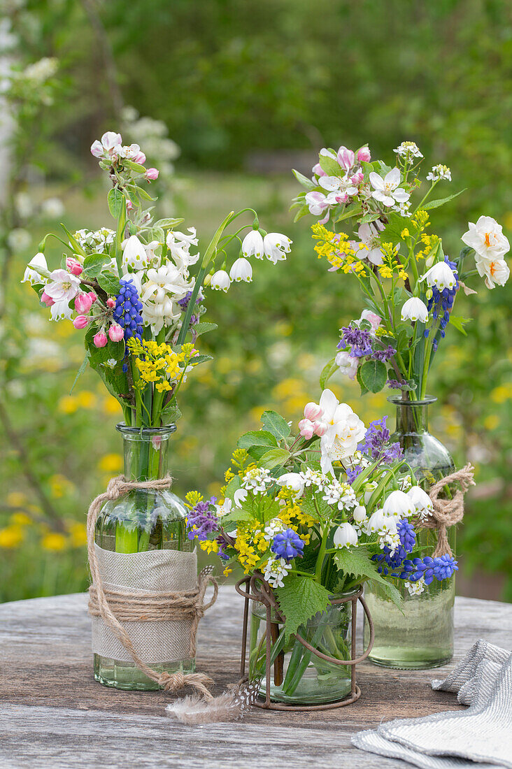 Meadow flower bouquets of mullein, garlic mustard, ornamental apple, hyacinth, Yellow rocketcress, catmint, narcissus in vases