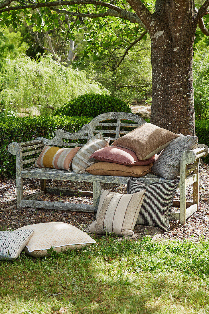 Vintage bench with cushions under a tree in the garden