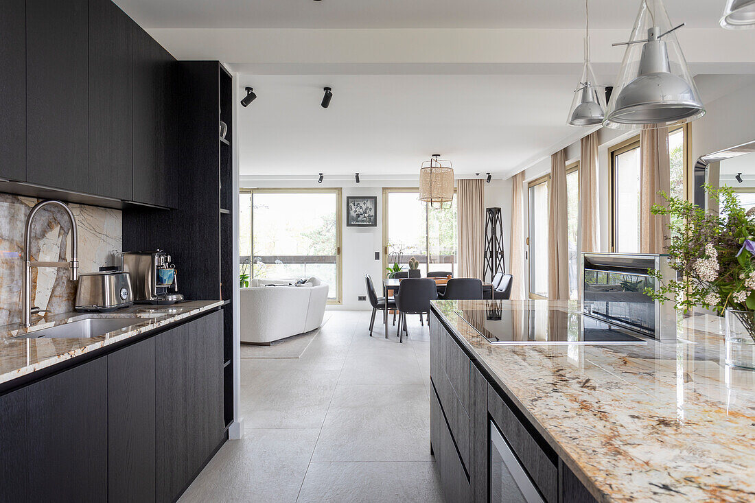 Elegant kitchen with black cupboard fronts and granite worktop in open plan living area