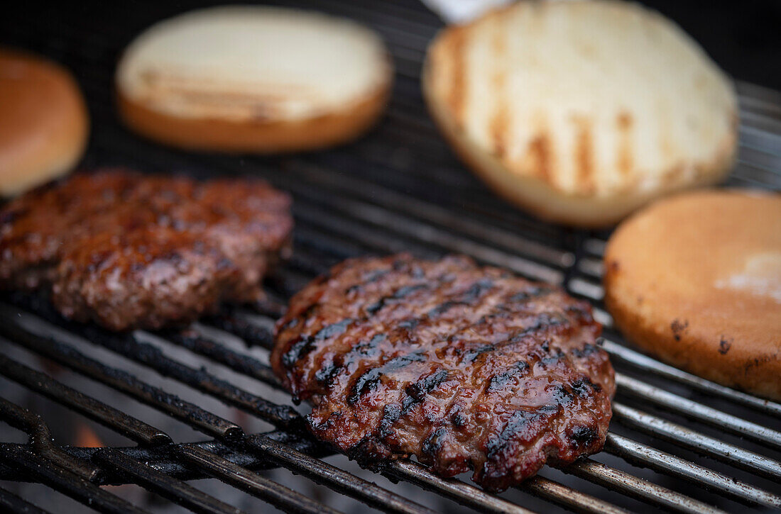 BBQ burger patties and burger buns on a grill