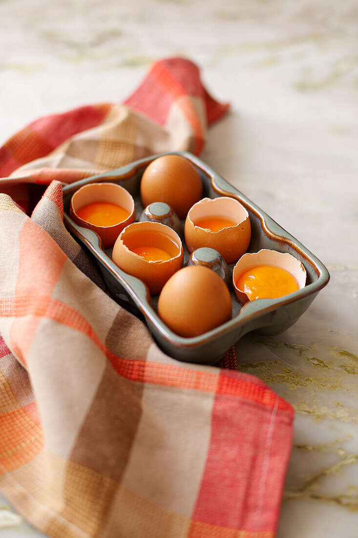 Fresh eggs, partially cracked, in an egg container