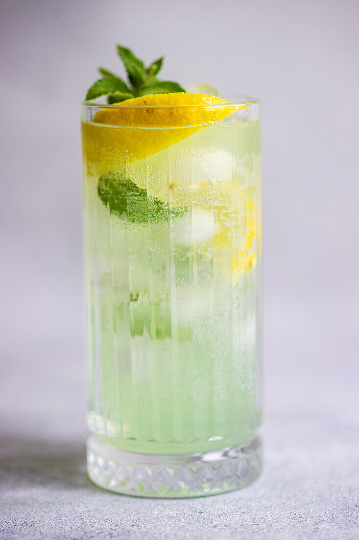 Mojito cocktail with mint and lemon served in the crystal glass on concrete table