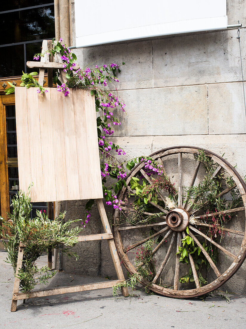 Easel and old wooden wheel entwined by bougainvillea, garden decoration