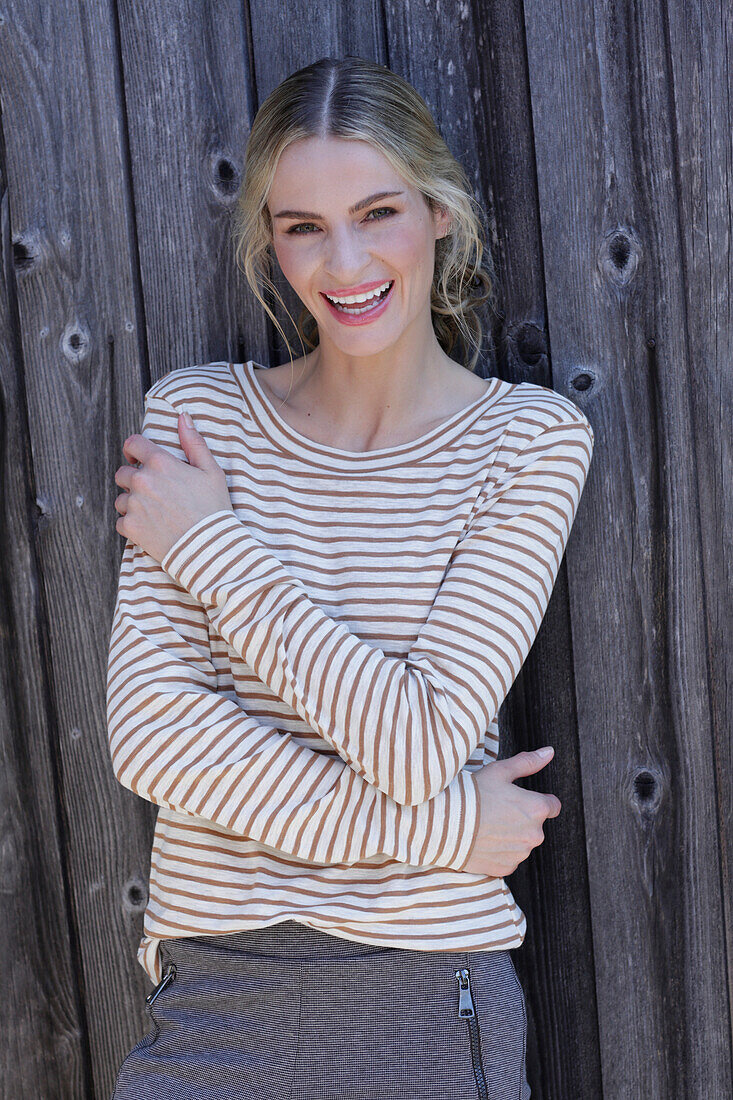 Young blond woman in striped shirt in front of board wall