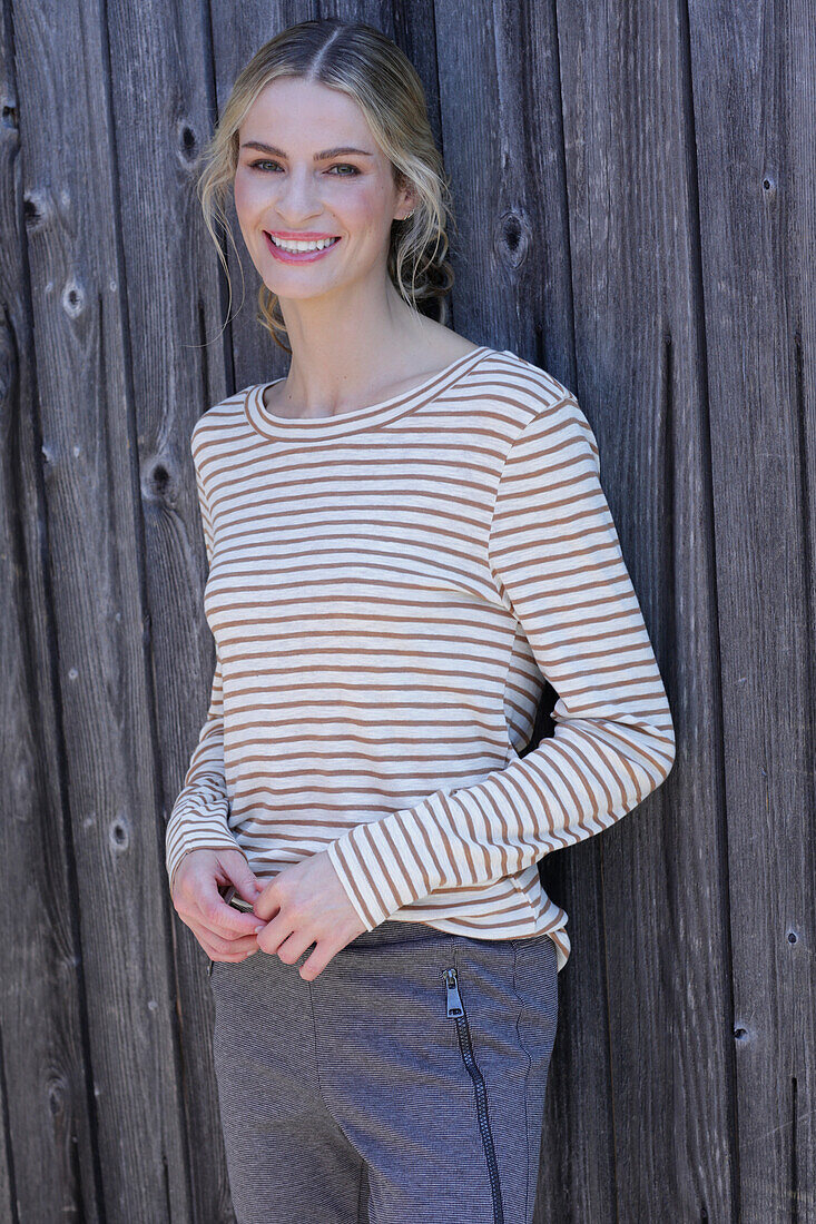 Young blond woman in striped shirt in front of board wall