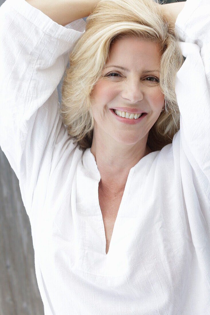 Reife blonde Frau in weißer Bluse mit V-Ausschnitt