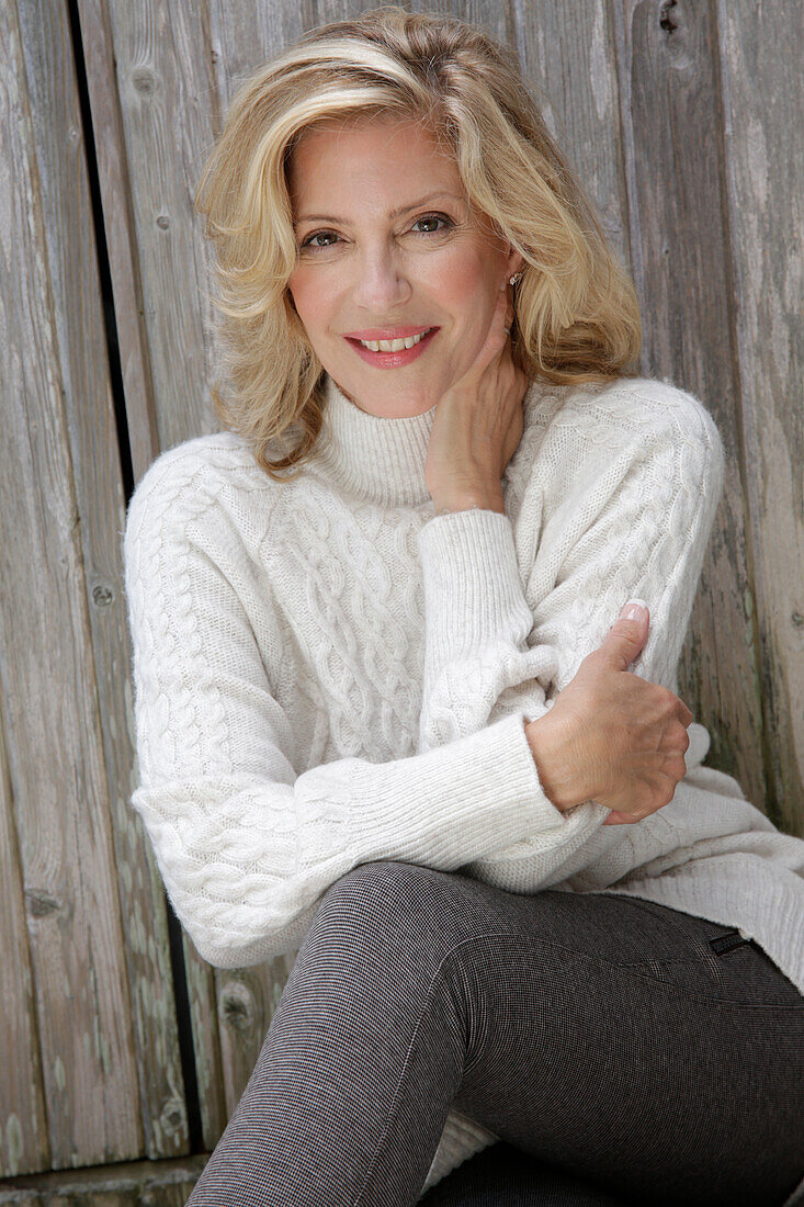 Mature blonde woman in white knitted jumper and grey leggings