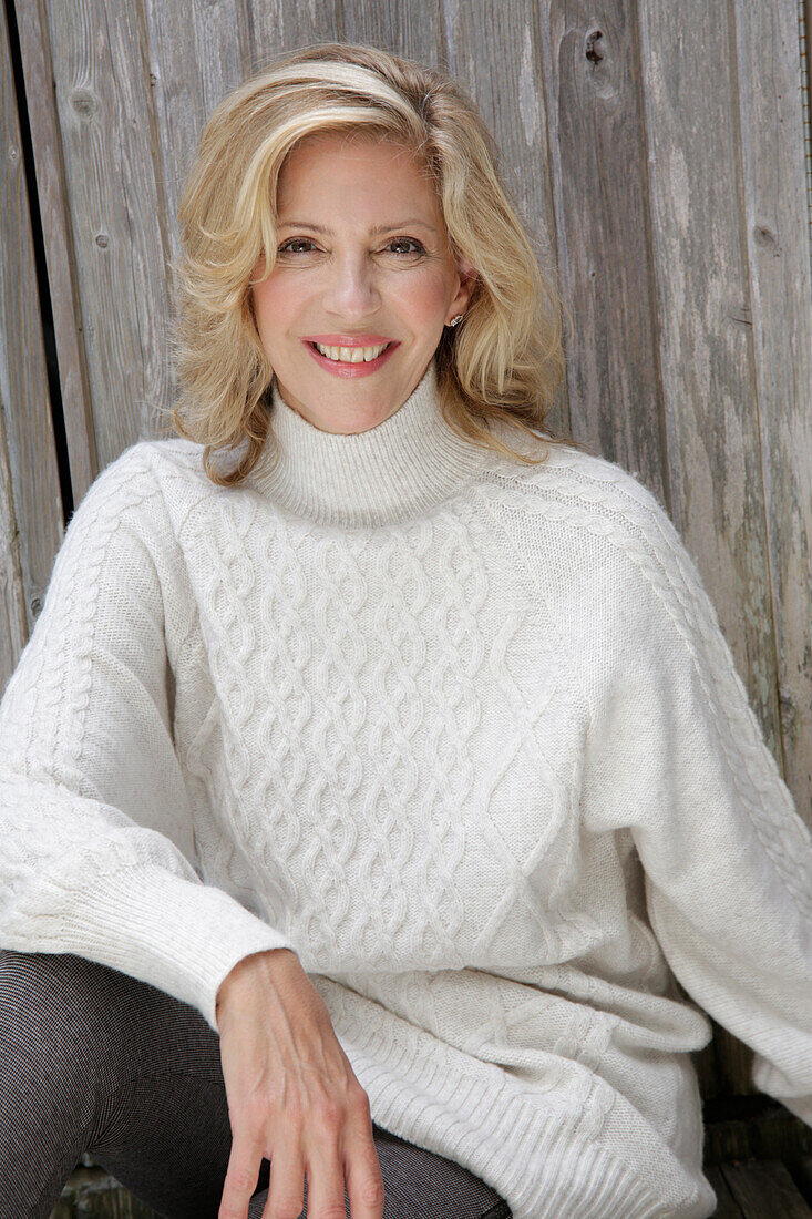 Mature blonde woman in white knitted jumper and grey leggings