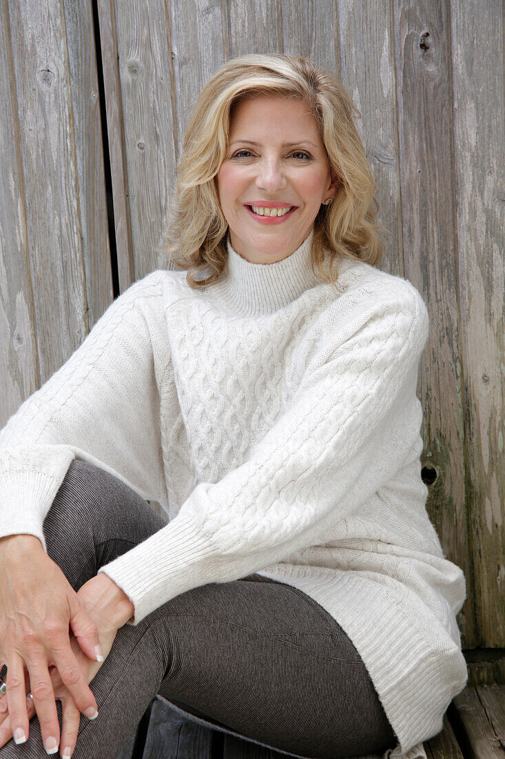 Mature blonde woman in white knitted jumper and grey leggings
